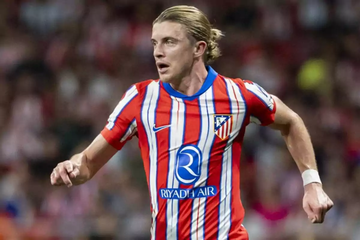 Jugador de fútbol con camiseta del Atlético de Madrid en el campo de juego.