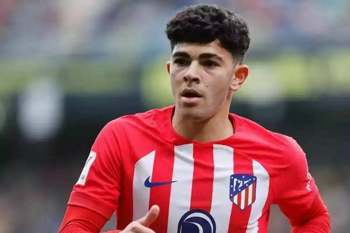 Jugador de fútbol con camiseta del Atlético de Madrid en el campo.