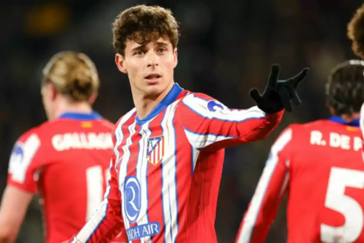 Un jugador de fútbol con el uniforme del Atlético de Madrid gesticula durante un partido.