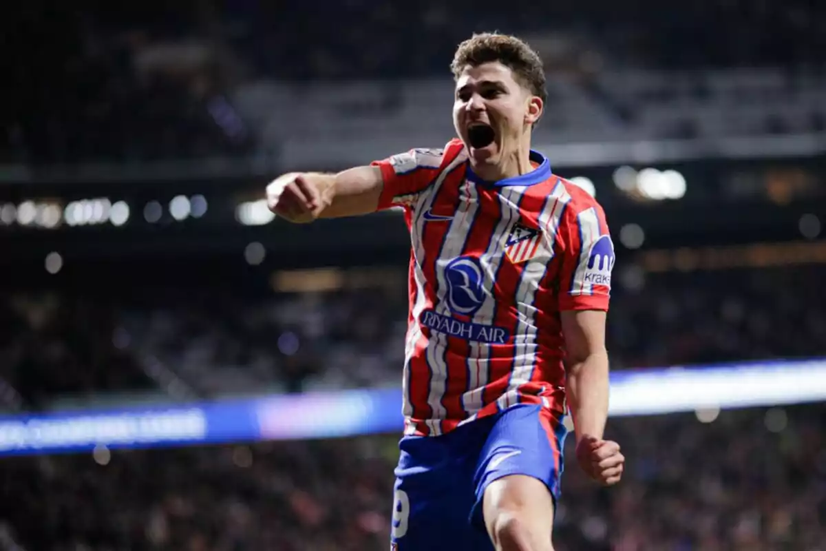 Un jugador de fútbol celebrando un gol con entusiasmo en un estadio iluminado.