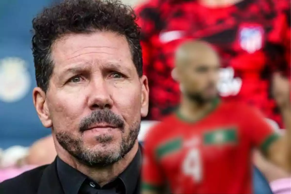 Un hombre con barba y cabello rizado en primer plano, con un jugador de fútbol desenfocado en el fondo.