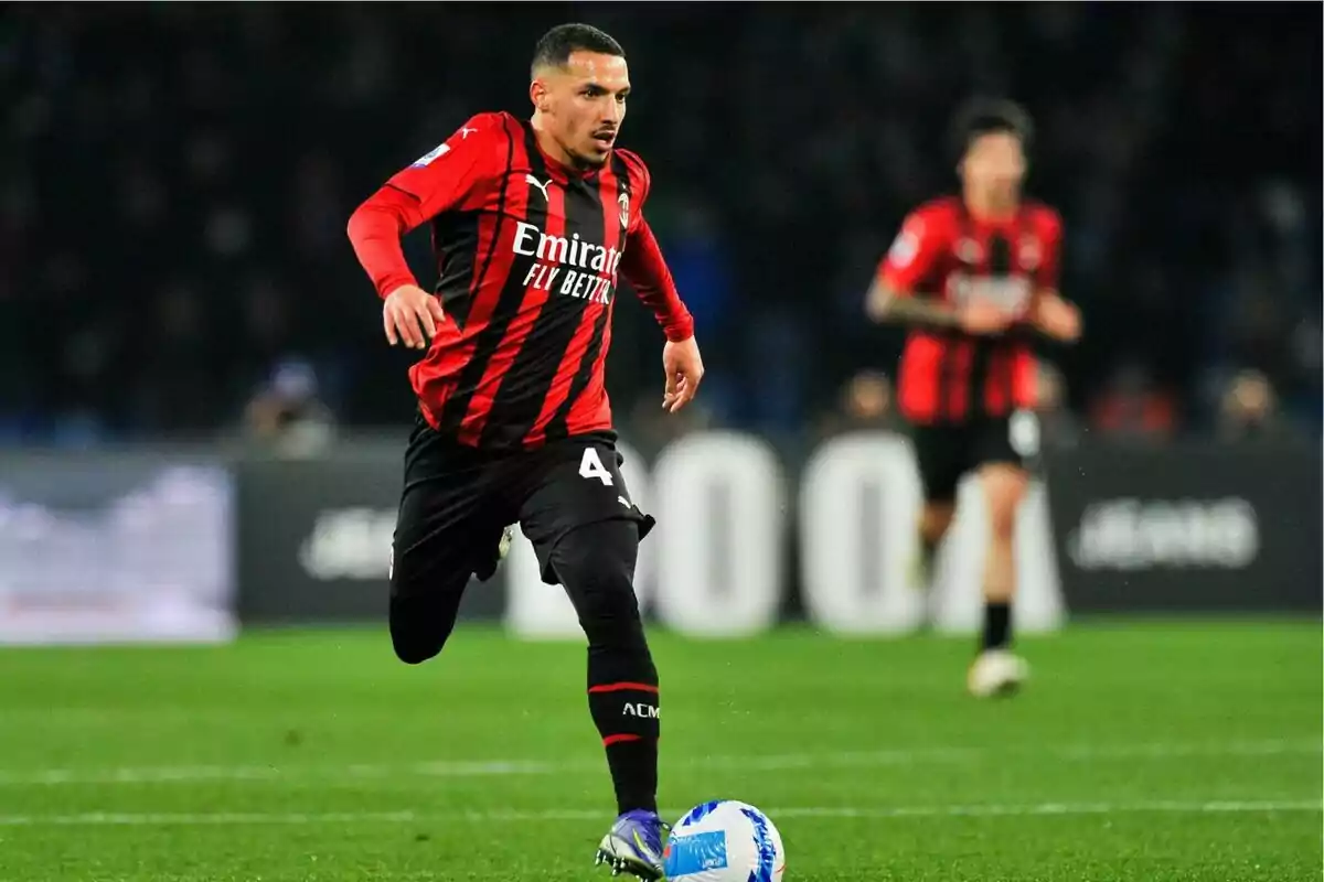 Soccer player in red and black uniform running with the ball on a playing field.