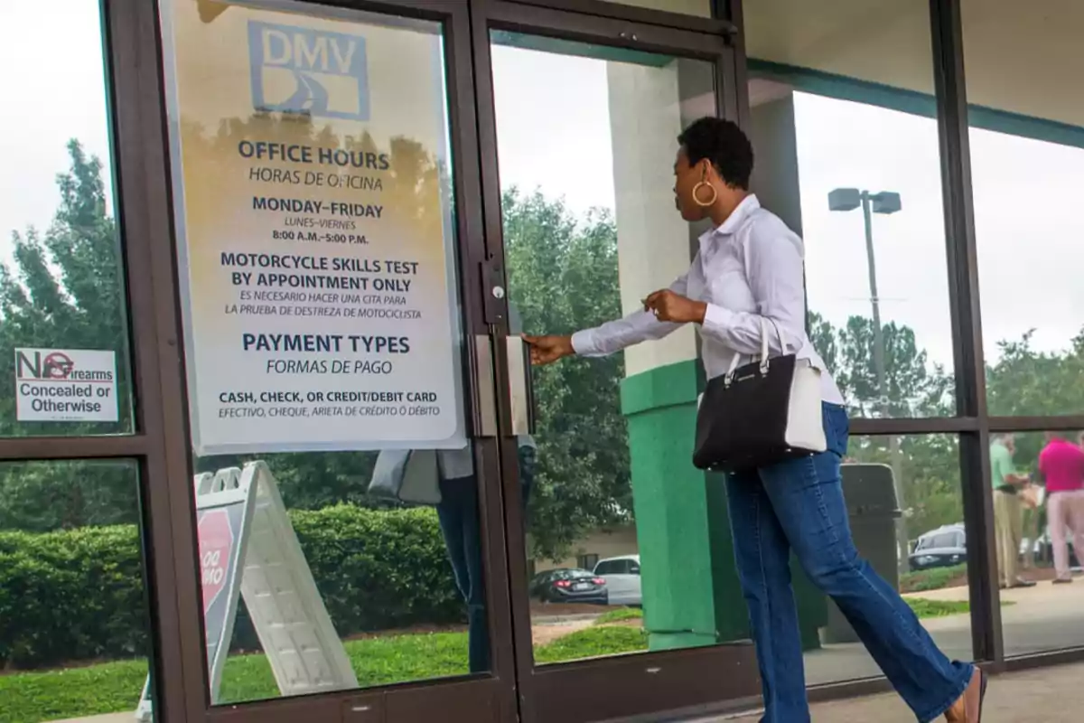 Woman opening the door of a DMV office with a sign displaying hours and payment methods at the entrance Woman opening the door of a DMV office with a sign displaying hours and payment methods at the entrance
