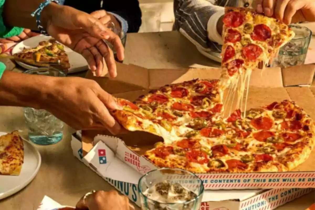 Several people sharing a pepperoni and jalapeño pizza at a table