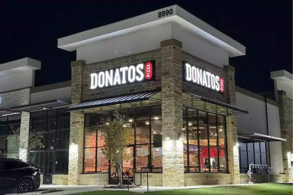Illuminated facade of a Donatos pizzeria at night with large windows and a bright sign