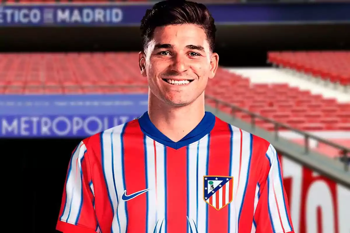 Un jugador de fútbol con la camiseta del Atlético de Madrid sonríe en un estadio.