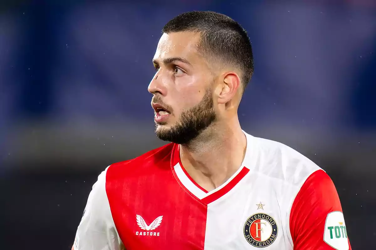 Un jugador de fútbol con uniforme rojo y blanco del Feyenoord Rotterdam en el campo de juego.