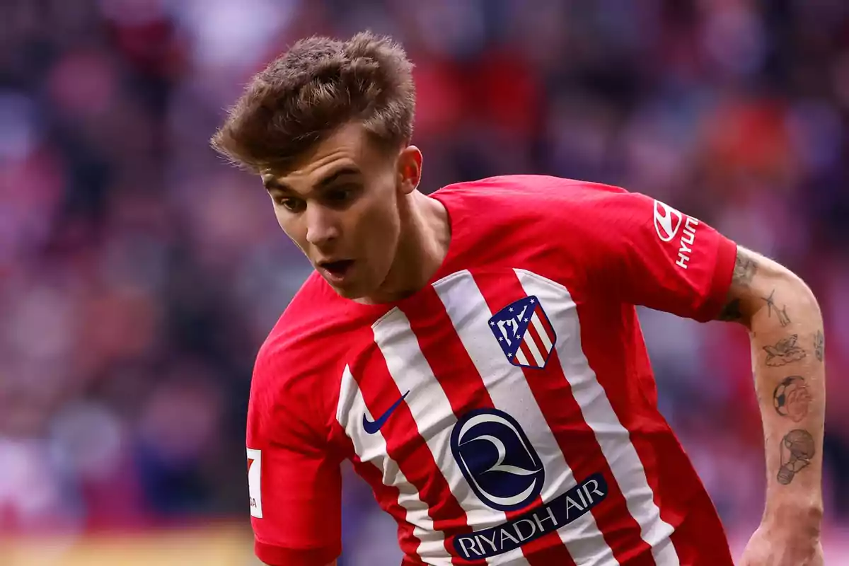 Jugador de fútbol con camiseta del Atlético de Madrid en acción durante un partido.