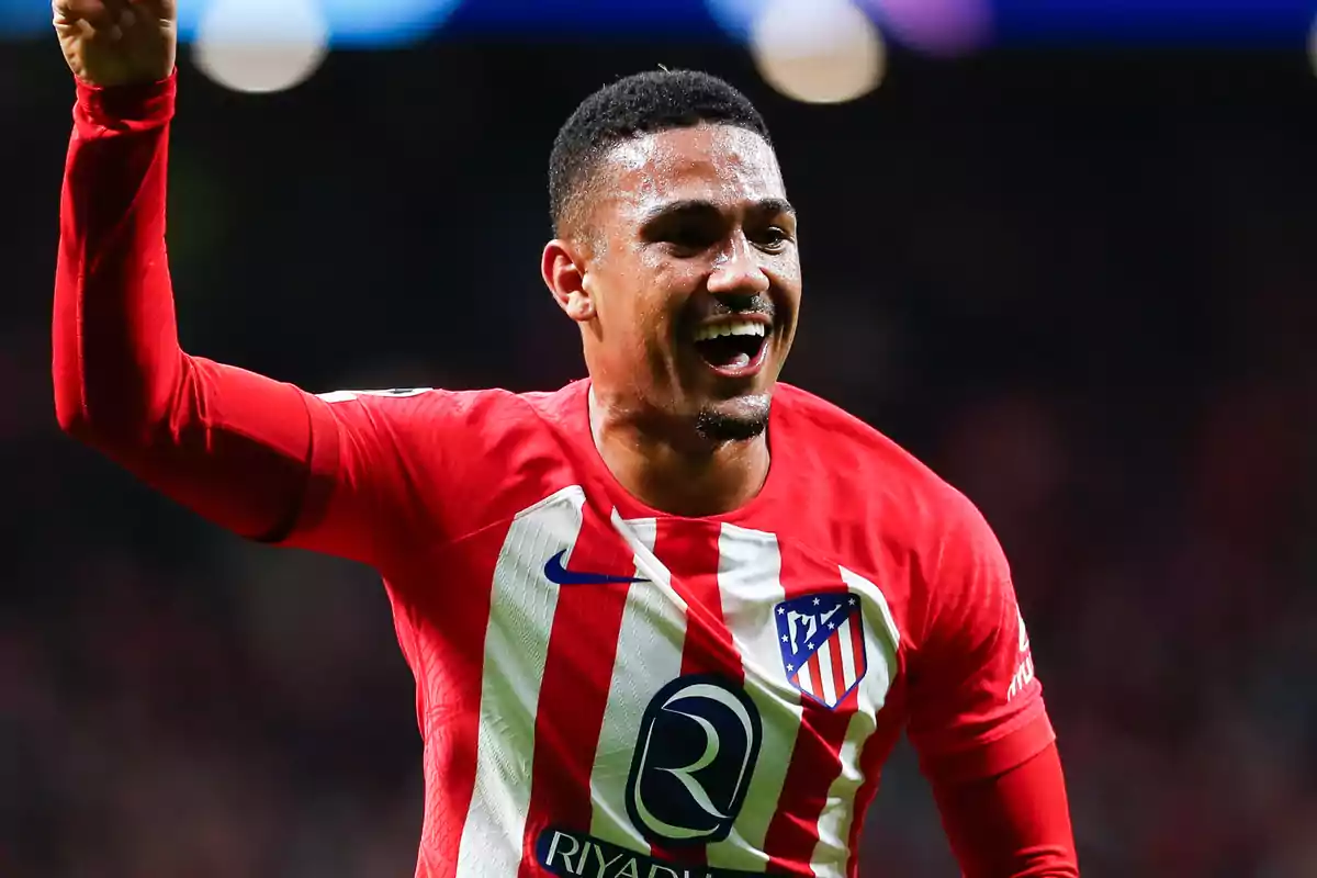 Jugador de fútbol con uniforme del Atlético de Madrid celebrando en el campo.