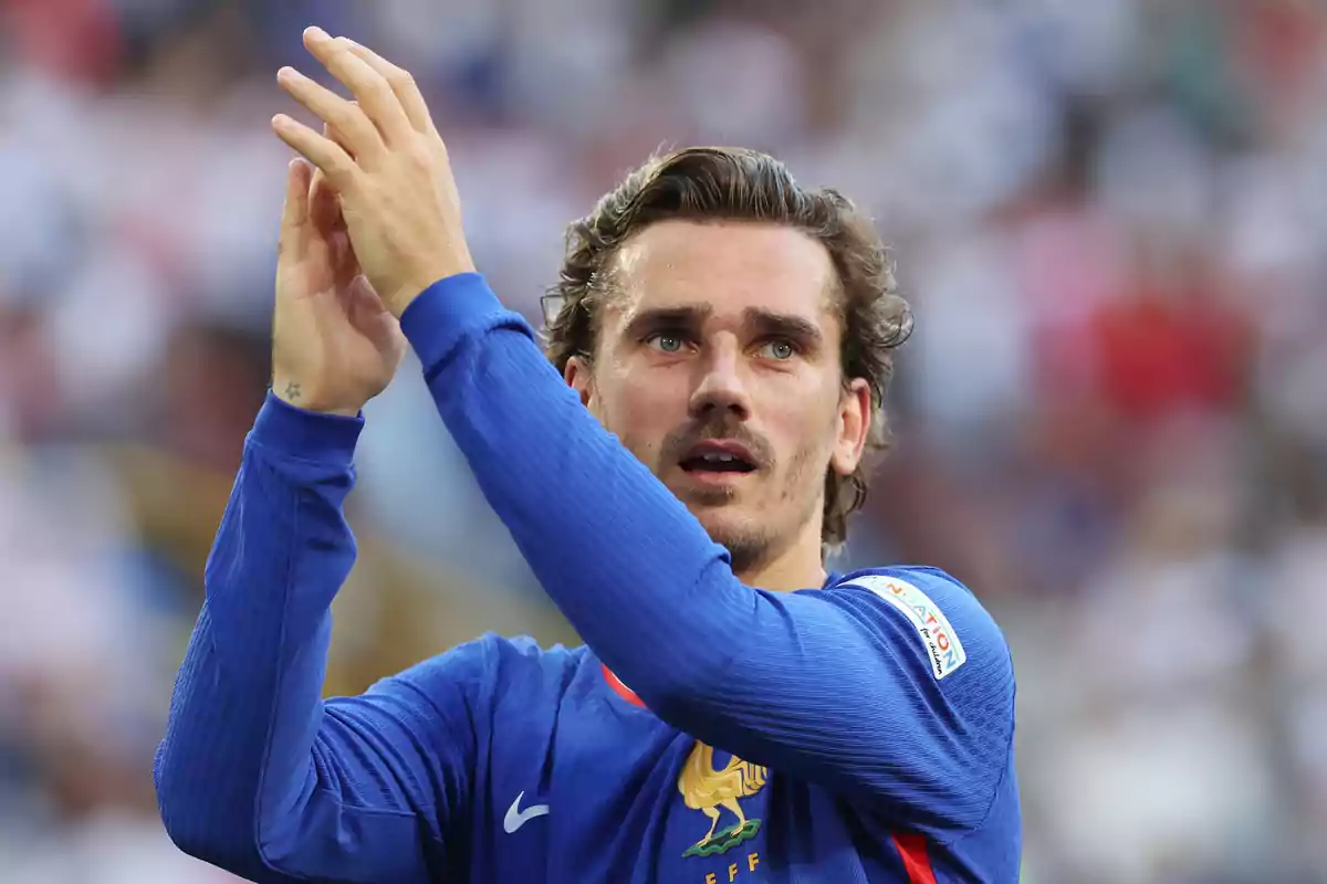 Jugador de fútbol aplaudiendo durante un partido con la camiseta de la selección de Francia.