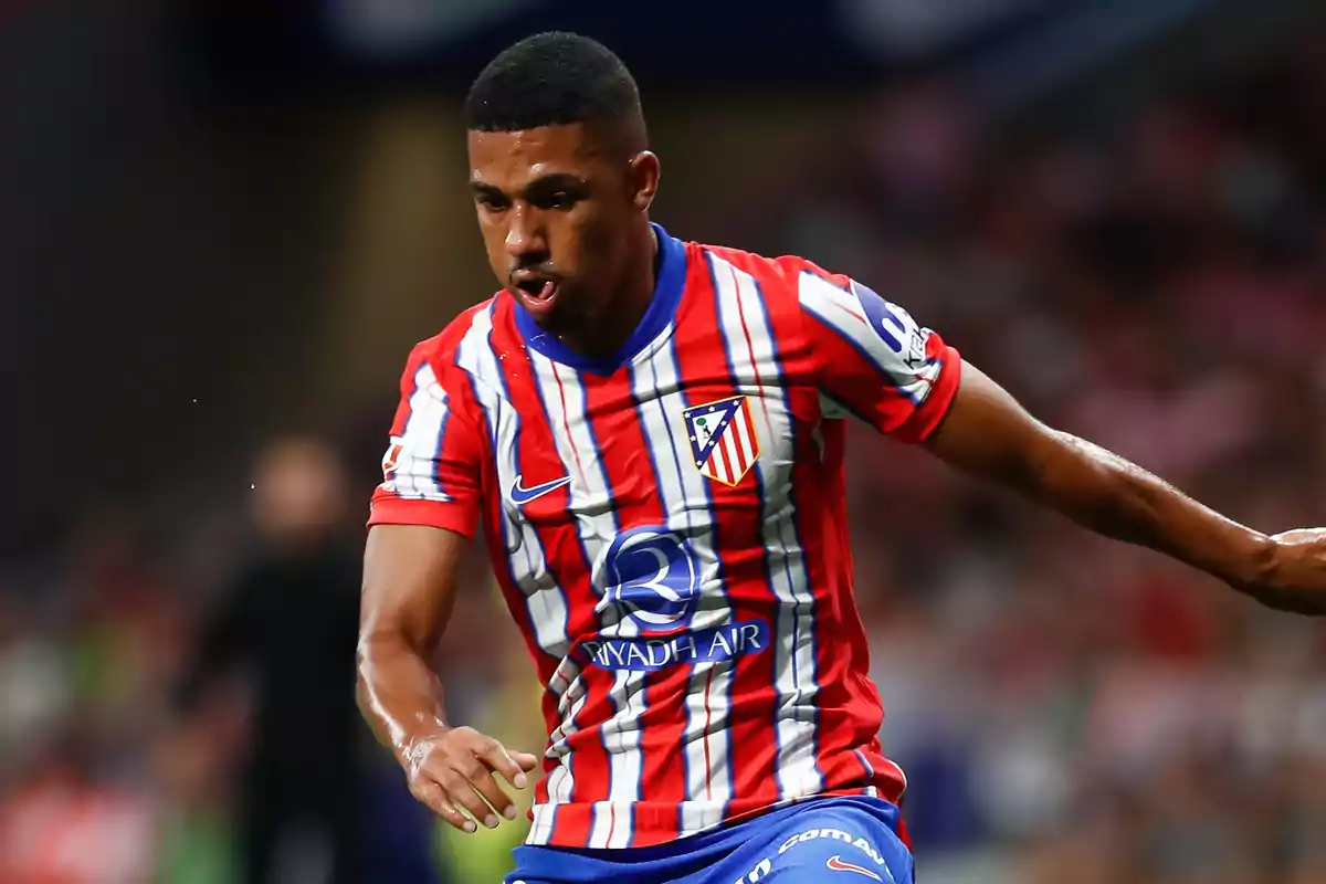 Jugador de fútbol con uniforme del Atlético de Madrid en acción durante un partido.