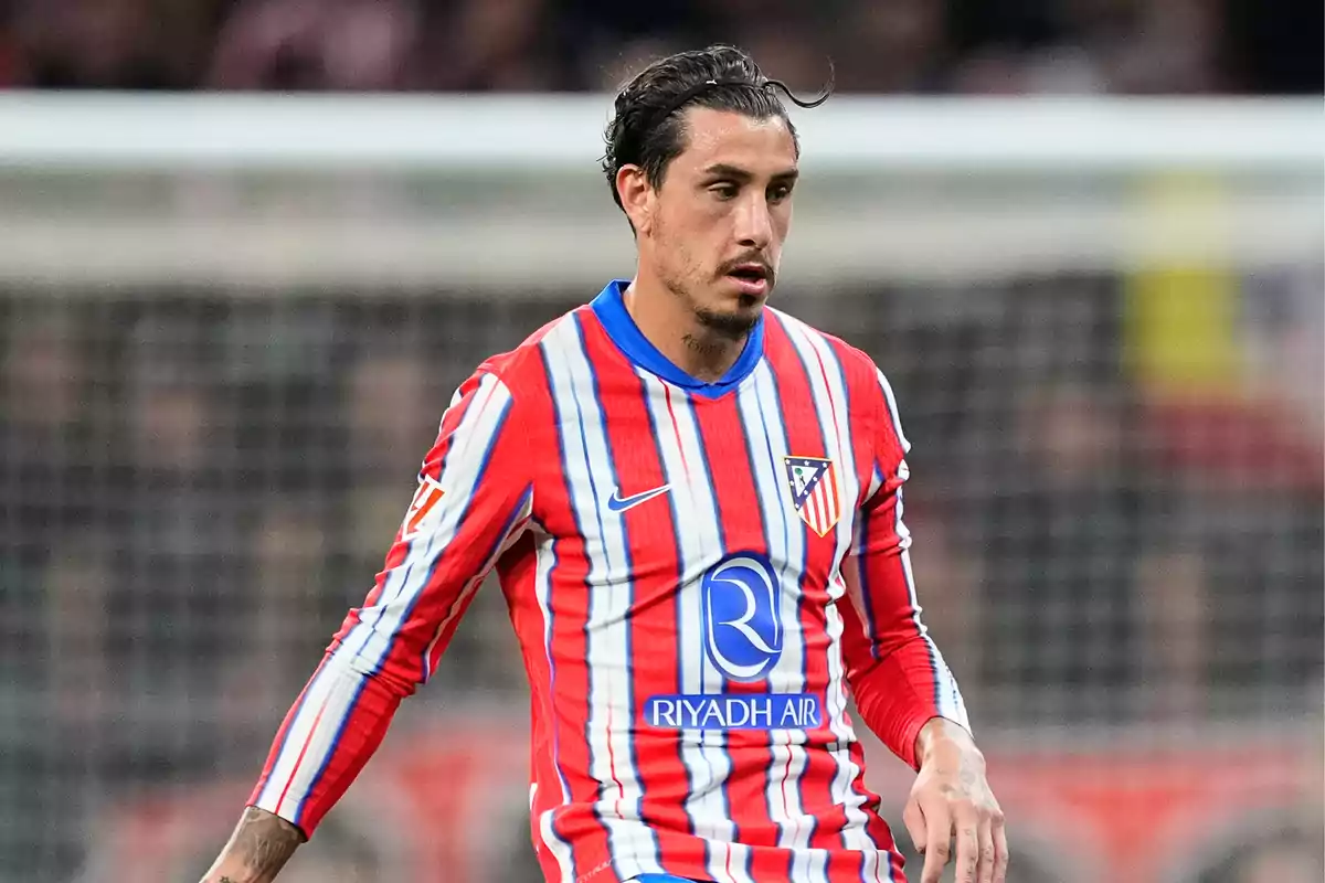 Jugador de fútbol con uniforme del Atlético de Madrid en el campo de juego.