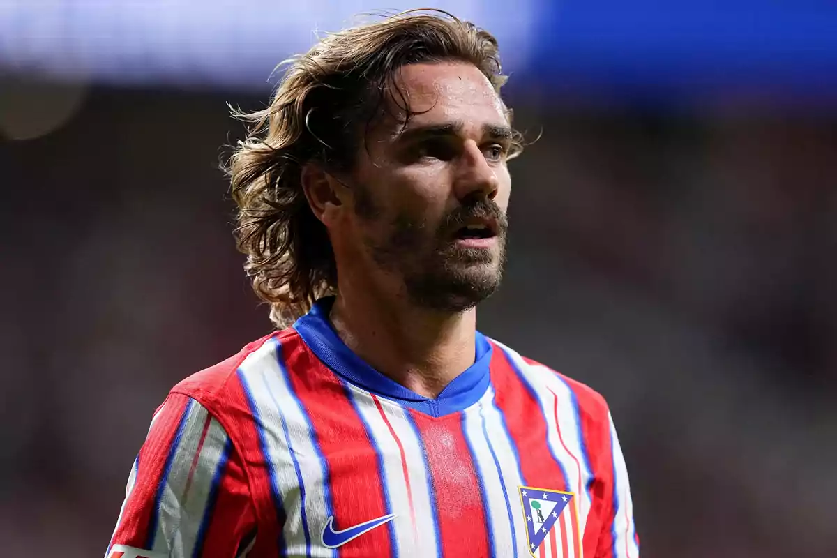 Jugador de fútbol con camiseta del Atlético de Madrid en el campo de juego.