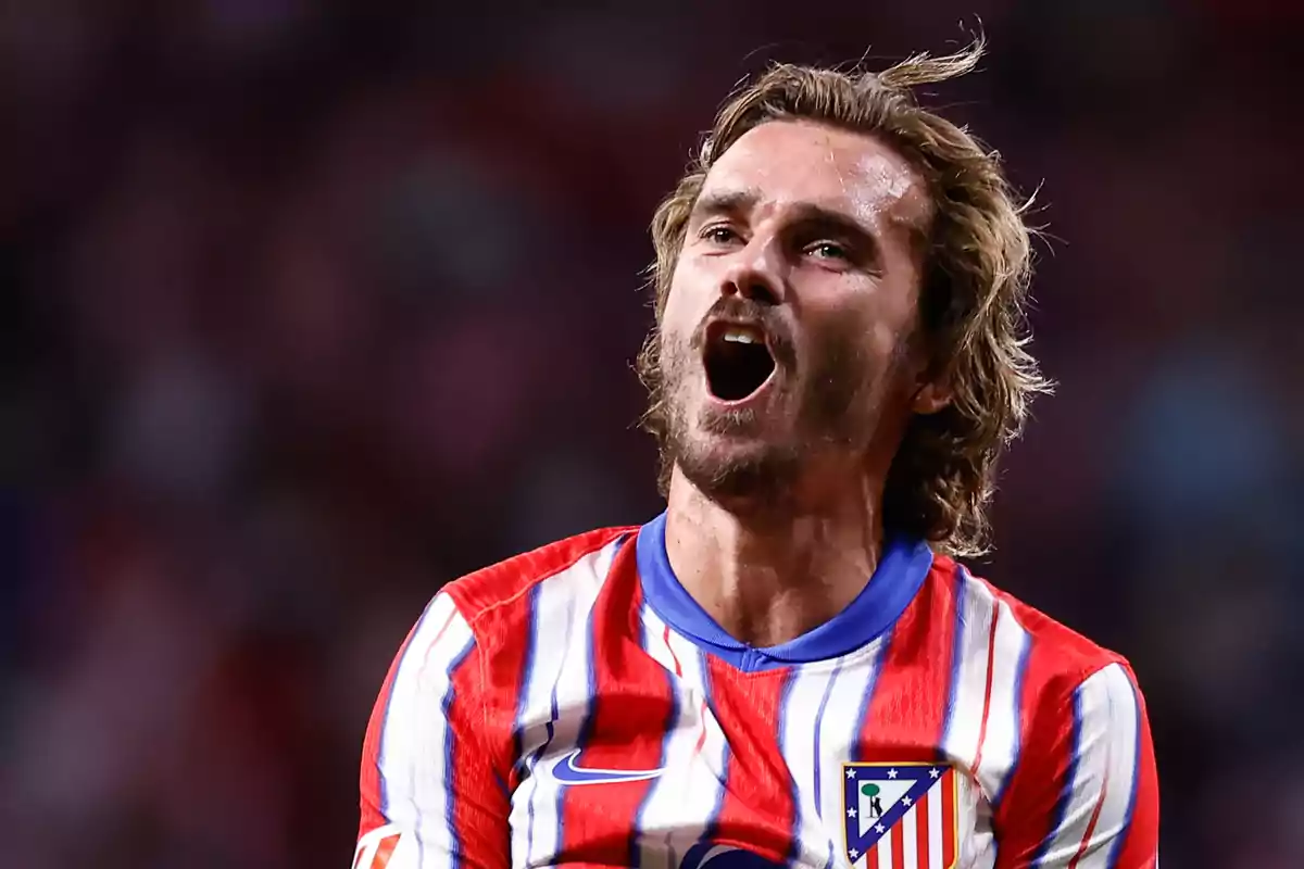 Jugador de fútbol con camiseta del Atlético de Madrid celebrando en el campo.