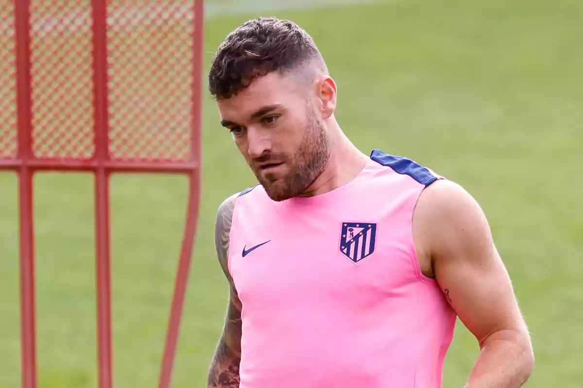 Un jugador de fútbol con camiseta rosa del Atlético de Madrid durante un entrenamiento en el campo.