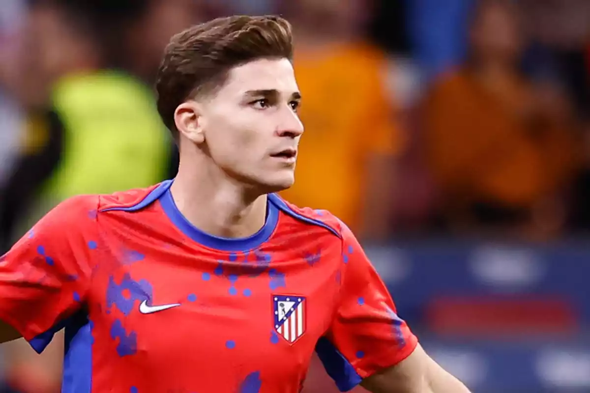 Un jugador de fútbol con camiseta roja y azul del Atlético de Madrid en el campo.