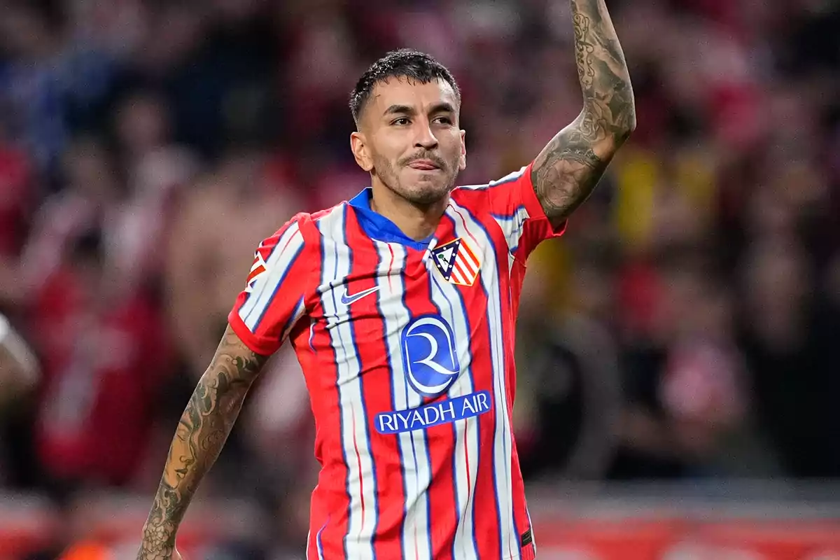 Un jugador de fútbol con uniforme rojo y blanco celebra en el campo.