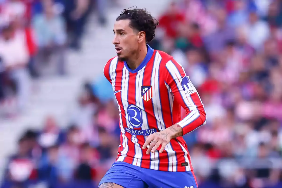 Jugador de fútbol con uniforme rojo y blanco a rayas en el campo durante un partido.