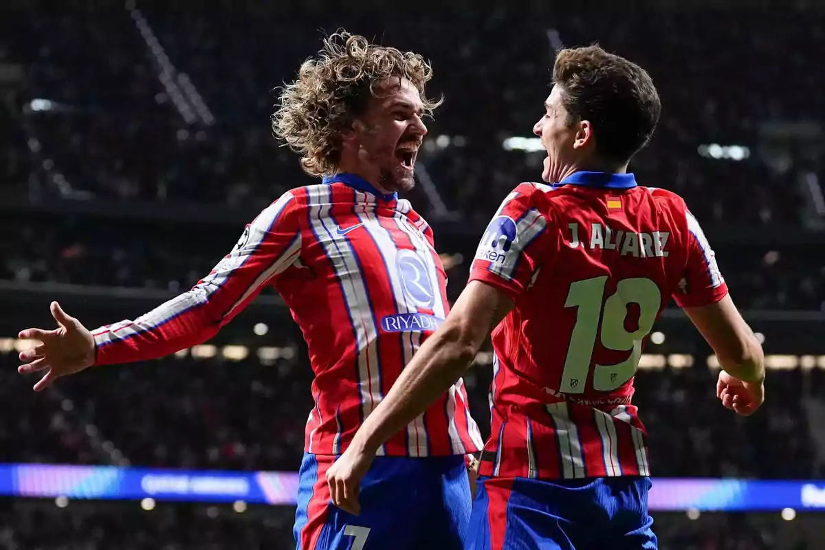 Dos jugadores de fútbol celebran un gol con entusiasmo en el campo.