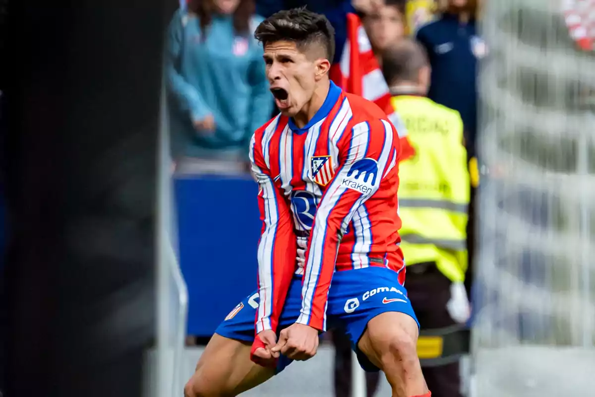 Un jugador de fútbol celebrando con entusiasmo en el campo, vistiendo un uniforme a rayas rojas y blancas.