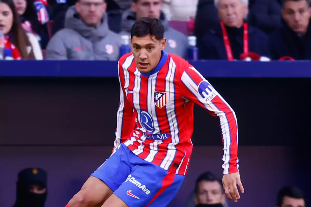 Jugador de fútbol del Atlético de Madrid en acción durante un partido, vistiendo el uniforme del equipo con rayas rojas y blancas.