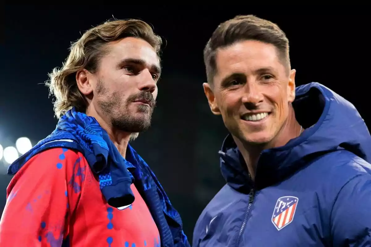 Dos hombres con ropa deportiva del Atlético de Madrid, uno con una camiseta roja y el otro con una chaqueta azul, conversan y sonríen en un entorno nocturno.