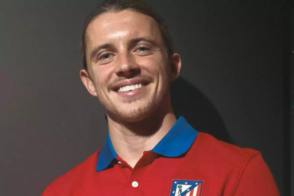 Un hombre sonriente con una camiseta roja del Atlético de Madrid.