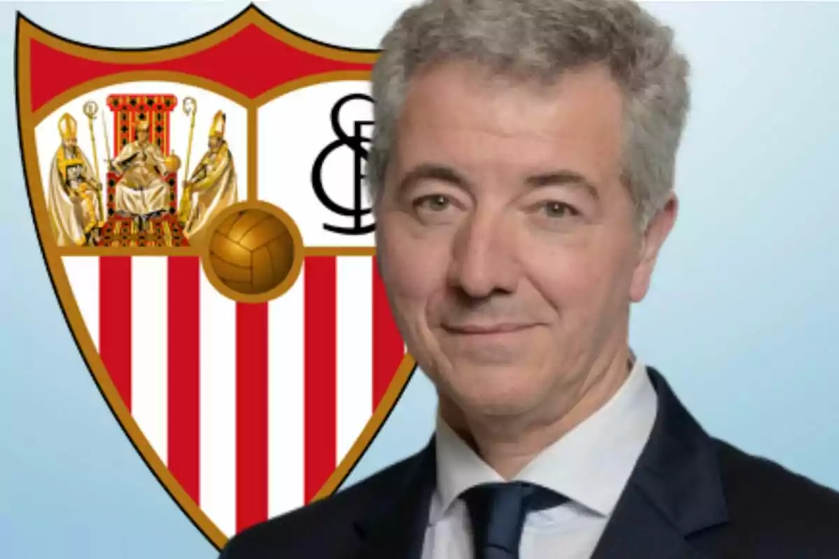 Un hombre con traje frente al escudo del Sevilla FC.