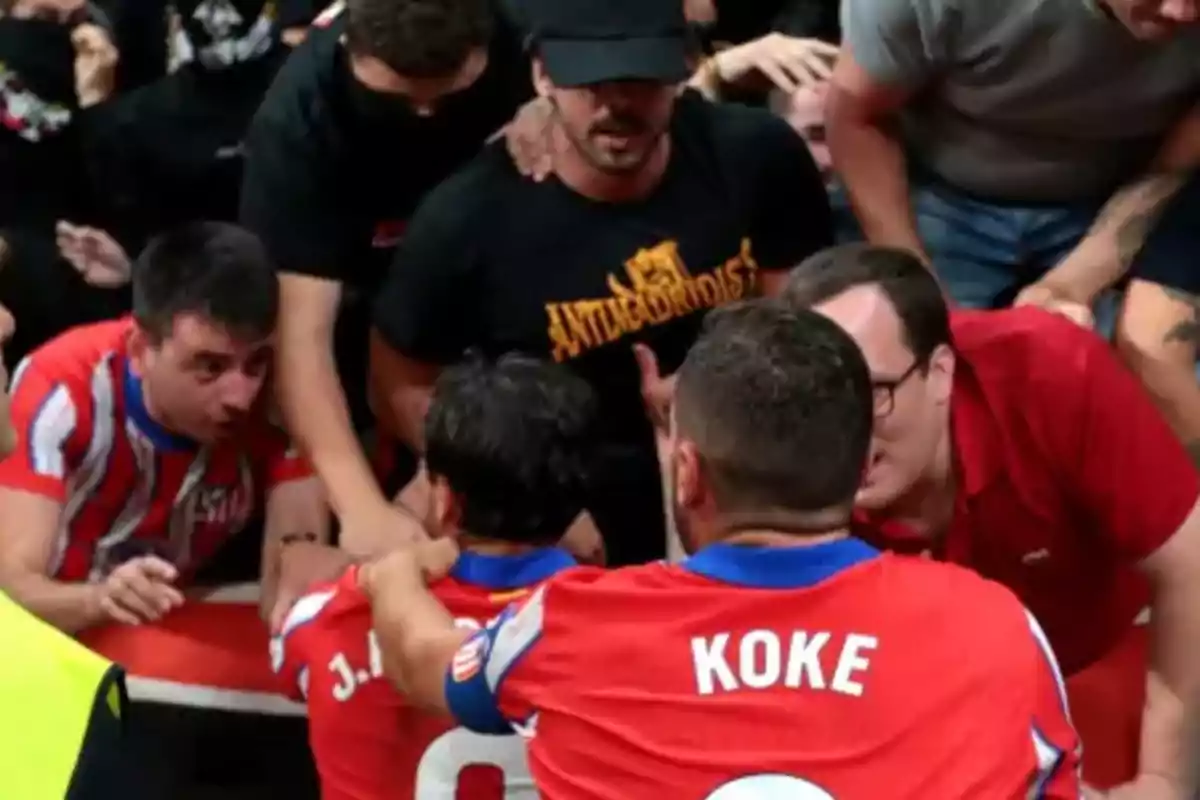 Jugadores de fútbol celebran con aficionados en las gradas durante un partido.