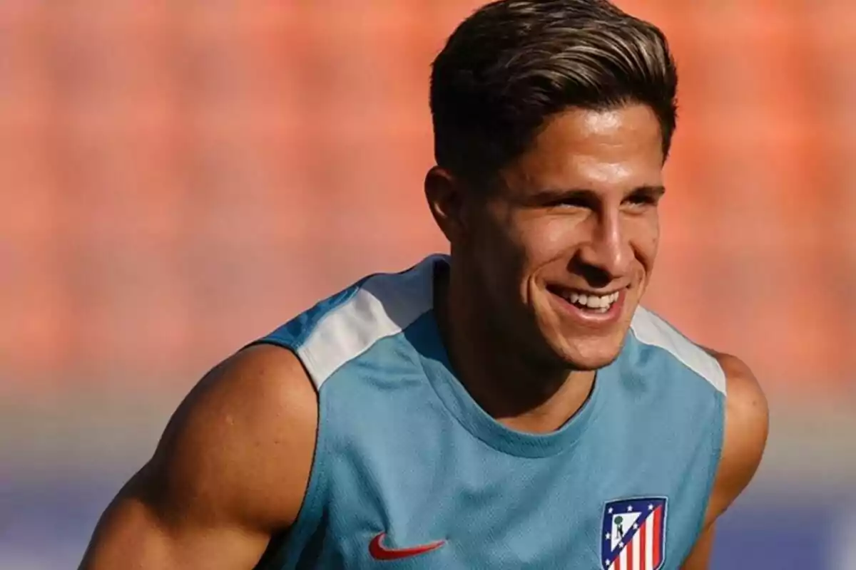 Un jugador de fútbol sonríe mientras entrena con una camiseta sin mangas del Atlético de Madrid.