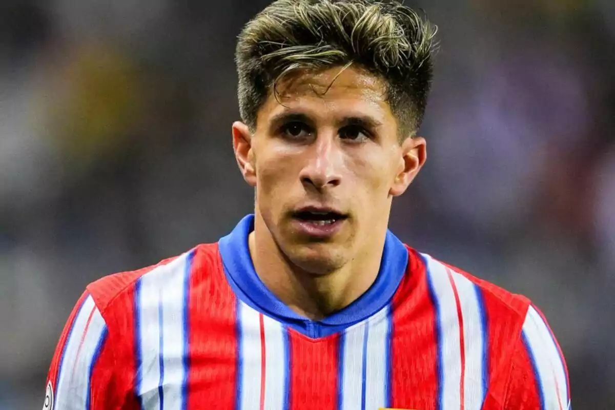 Un jugador de fútbol con camiseta de rayas rojas, blancas y azules en el campo.