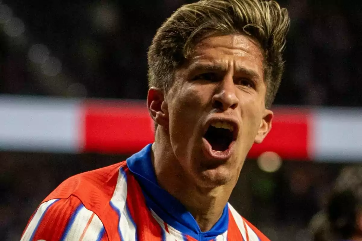 Un jugador de fútbol con uniforme a rayas rojas y blancas celebra con expresión de emoción en el campo.