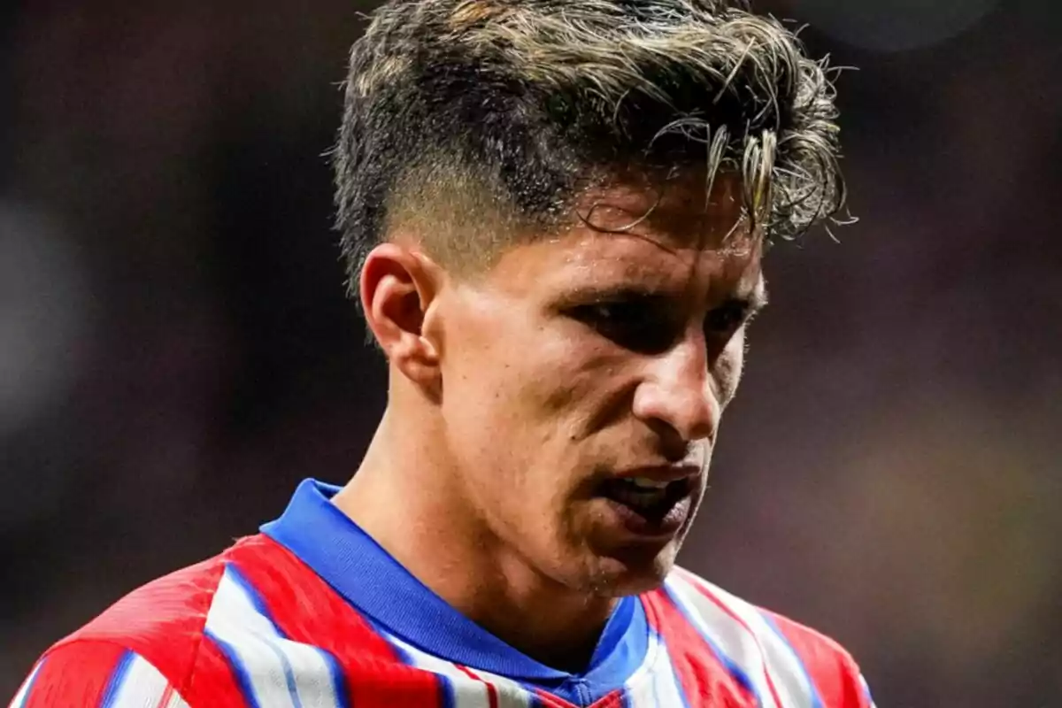 A player with a serious expression and a red and white striped jersey.