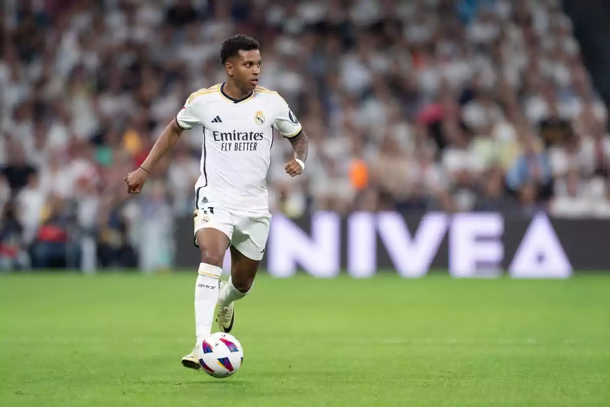 Un jugador de fútbol del Real Madrid corriendo con el balón en un partido.