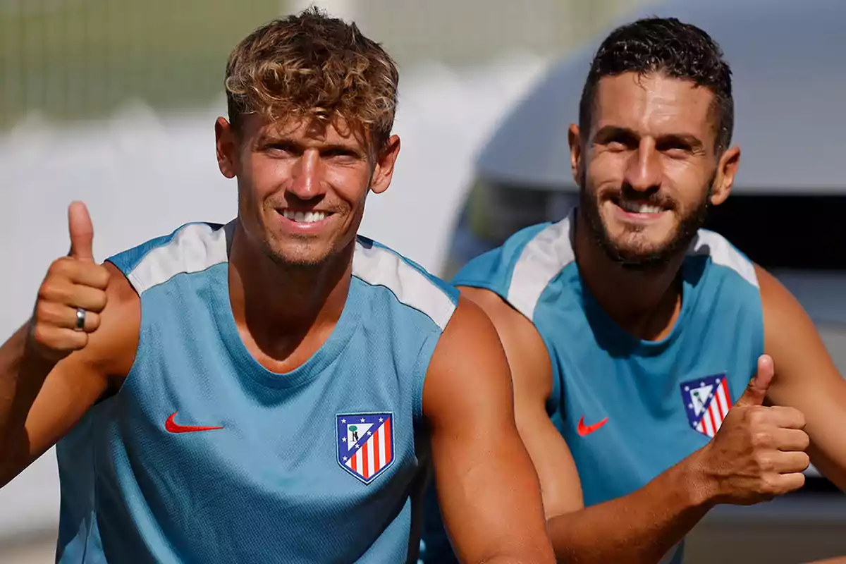 Dos hombres con camisetas de entrenamiento del Atlético de Madrid sonríen y levantan el pulgar.