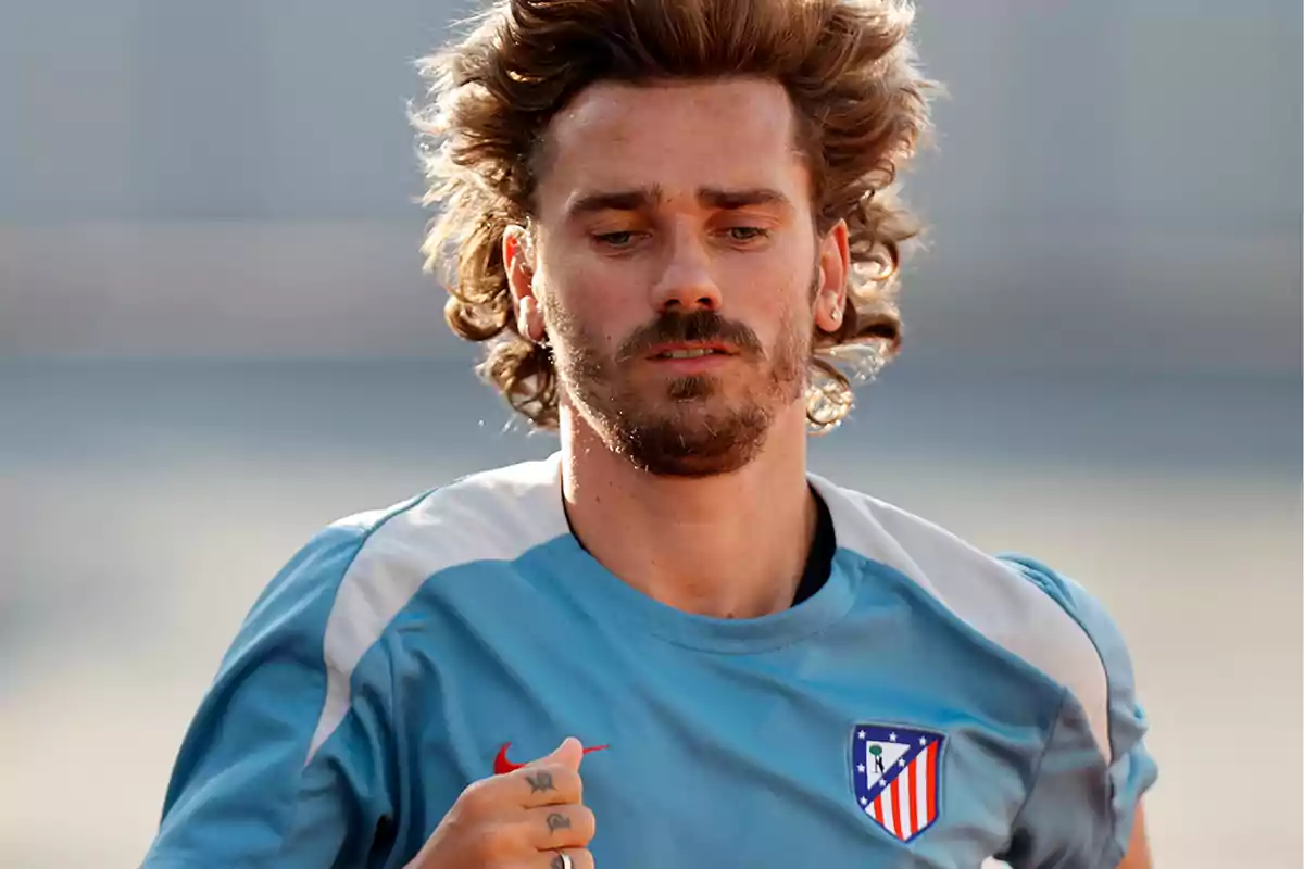 Un jugador de fútbol con camiseta de entrenamiento azul claro del Atlético de Madrid corriendo.