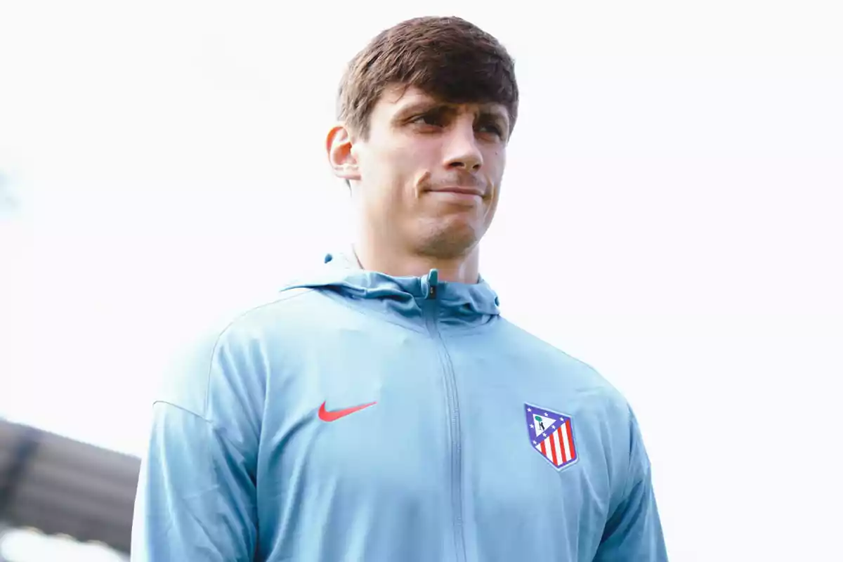 Un hombre con una chaqueta azul claro con el logo del Atlético de Madrid y el símbolo de Nike.