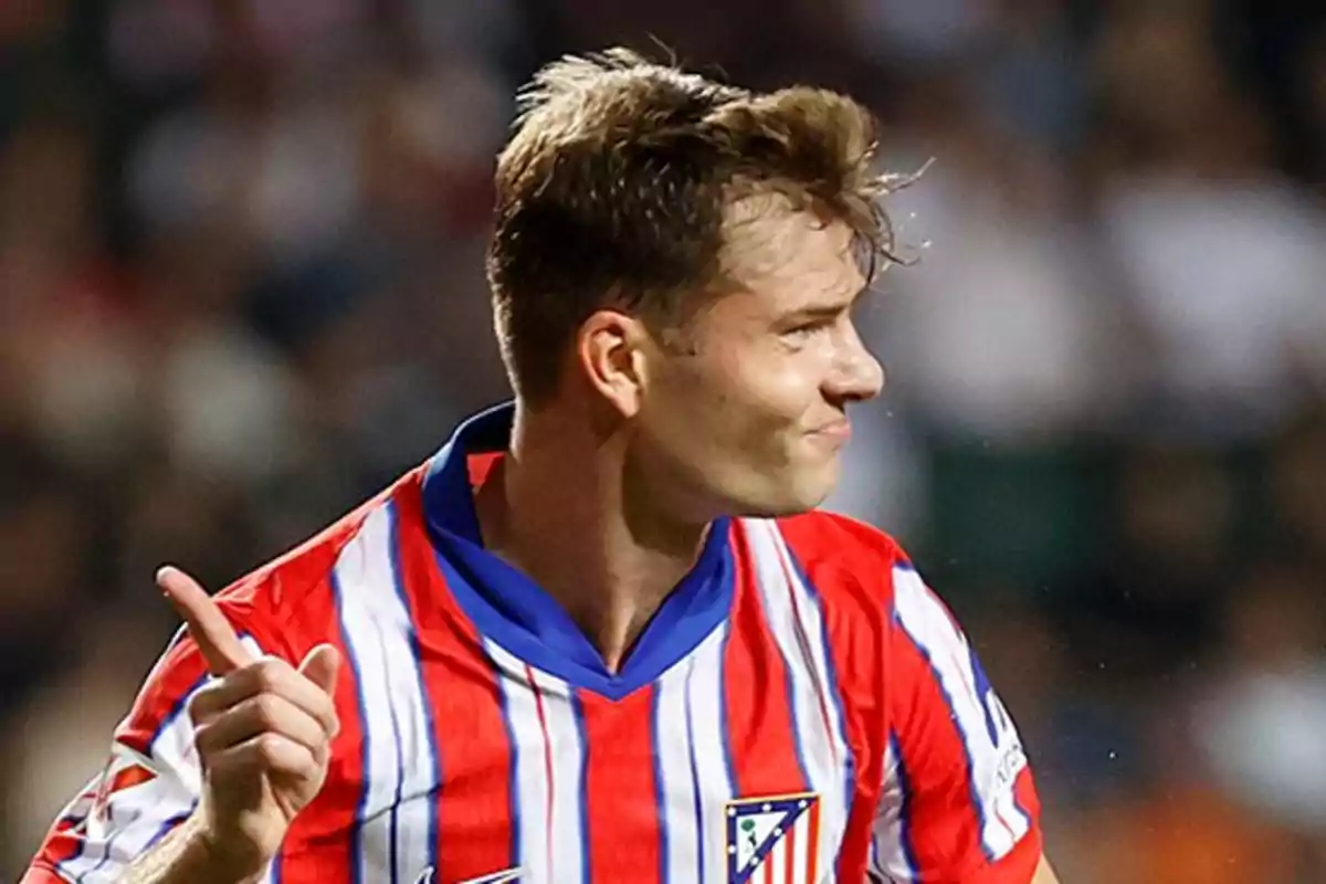 Jugador de fútbol con la camiseta del Atlético de Madrid señalando con el dedo índice.