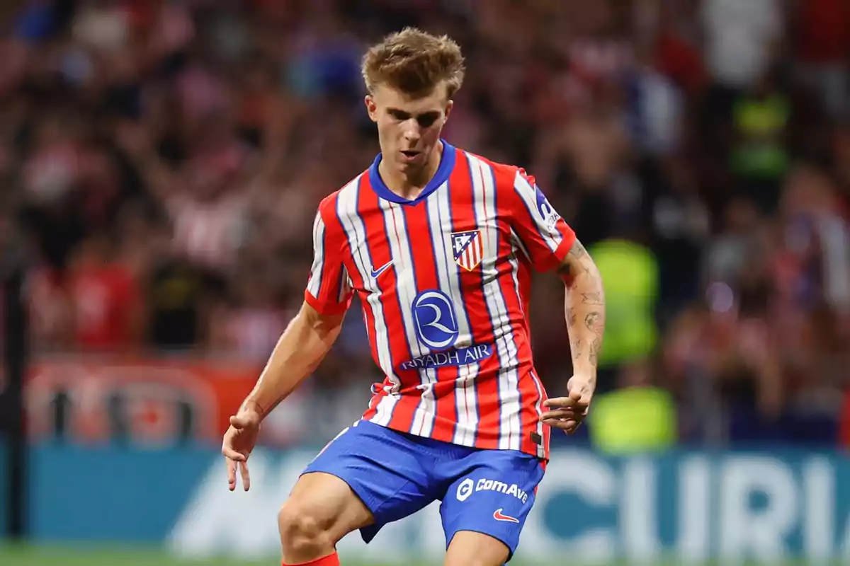 Jugador de fútbol con uniforme del Atlético de Madrid en acción durante un partido.