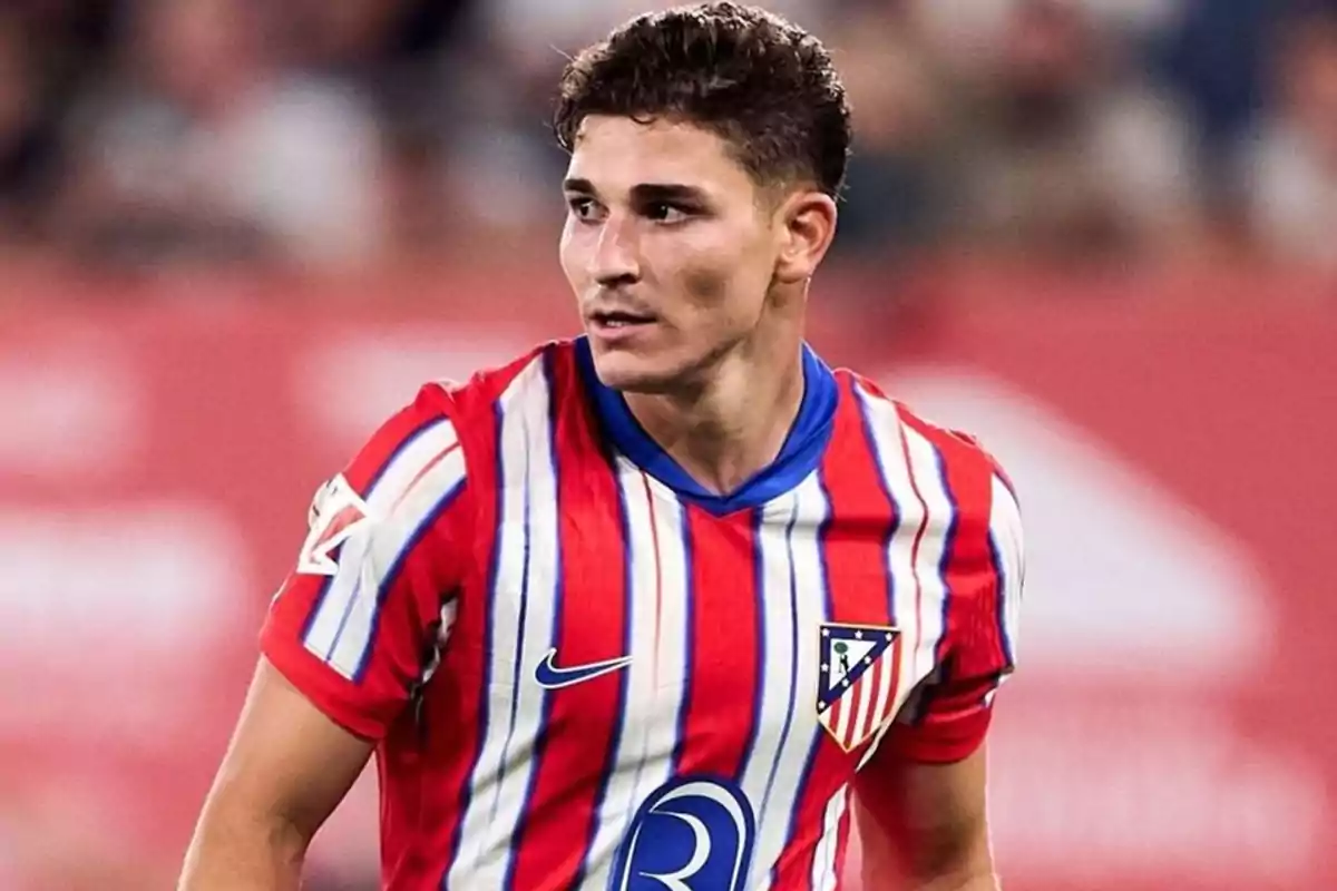 Jugador de fútbol con camiseta del Atlético de Madrid en el campo de juego.