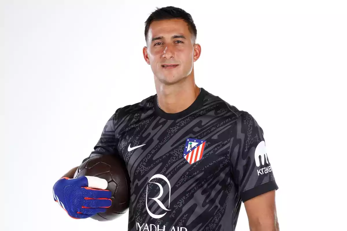 A soccer player in a black uniform and gloves holds a ball. A soccer player in a black uniform and gloves holds a ball.