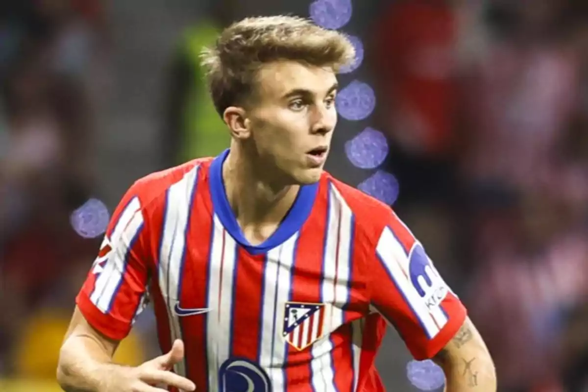 Jugador de fútbol con camiseta del Atlético de Madrid en el campo de juego.