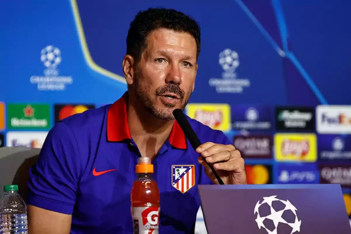 Un hombre con una camiseta del Atlético de Madrid hablando en una conferencia de prensa de la UEFA Champions League.