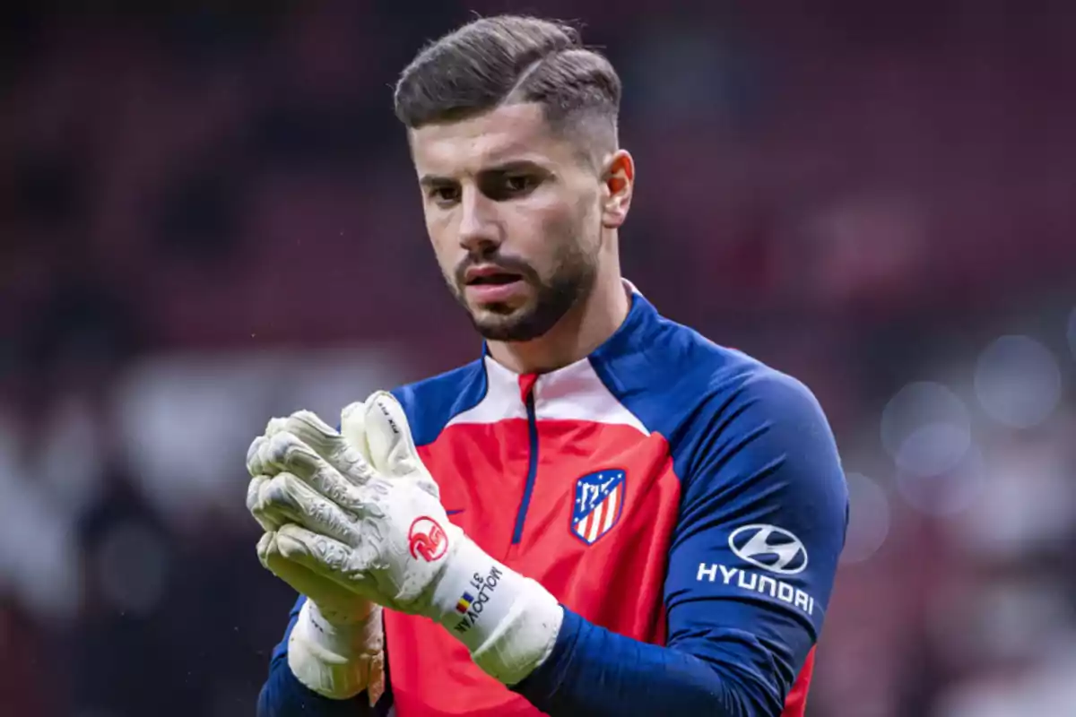 Un jugador de fútbol con uniforme de entrenamiento del Atlético de Madrid y guantes de portero.