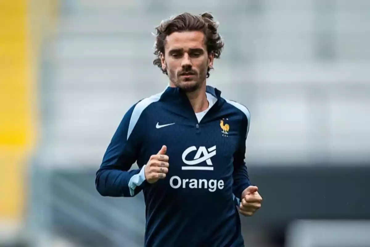 Un jugador de fútbol con uniforme de entrenamiento de la selección de Francia corriendo en un campo.