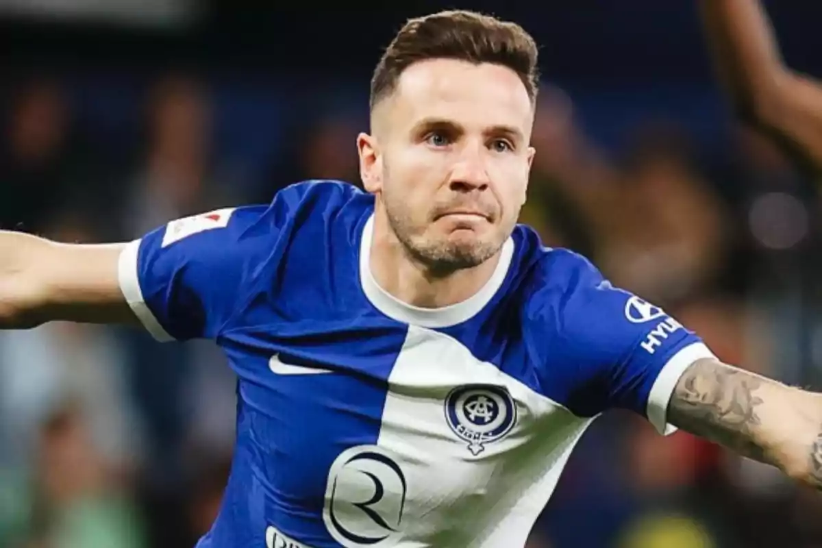 Jugador de fútbol con uniforme azul y blanco en acción durante un partido.