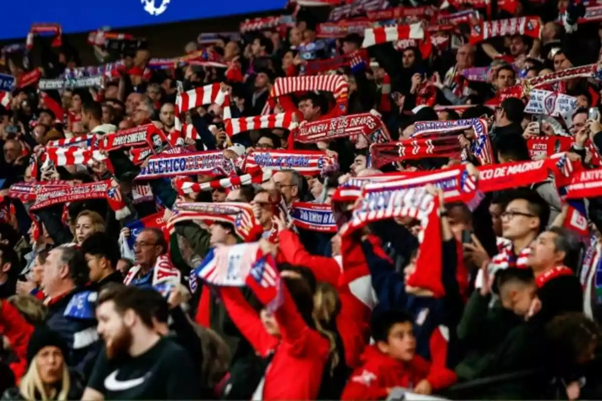 Aficionados de fútbol con bufandas rojas y blancas en un estadio.