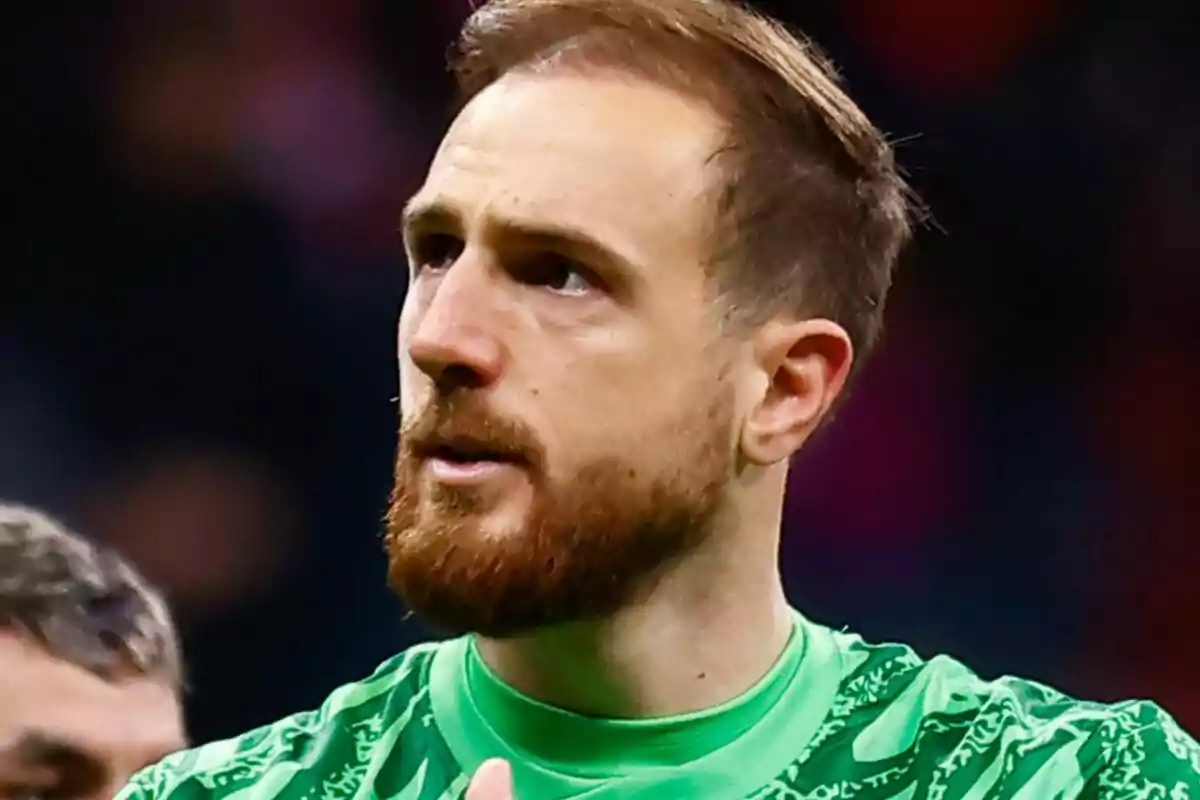 Un hombre con barba y cabello corto lleva una camiseta verde y parece estar en un evento deportivo.