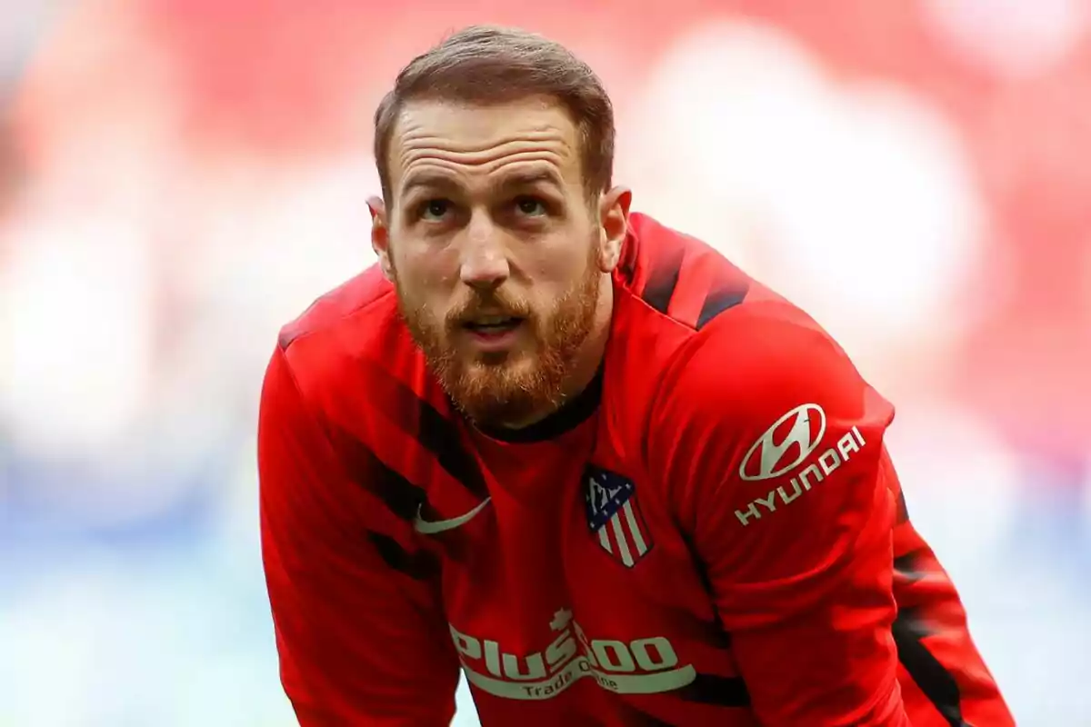 Jugador de fútbol con uniforme rojo del Atlético de Madrid en el campo.