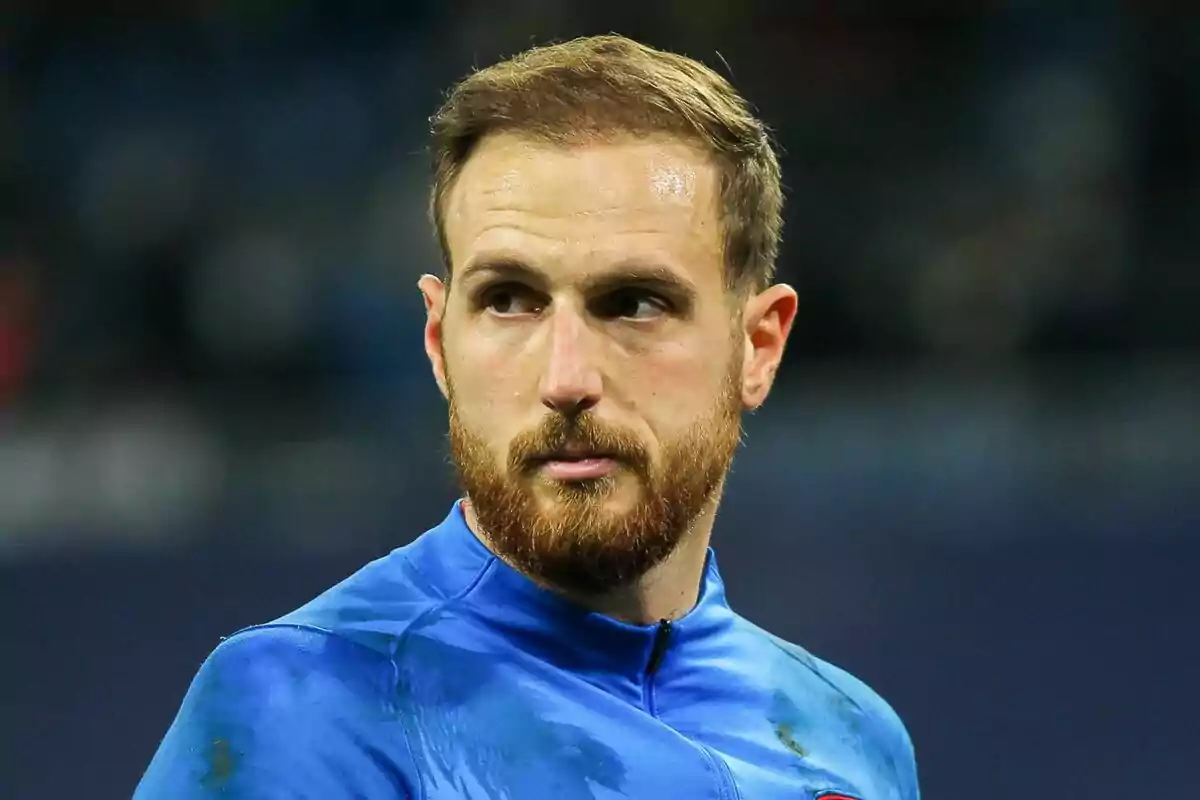 Un hombre con barba y cabello corto, vestido con una camiseta azul, mirando hacia un lado.